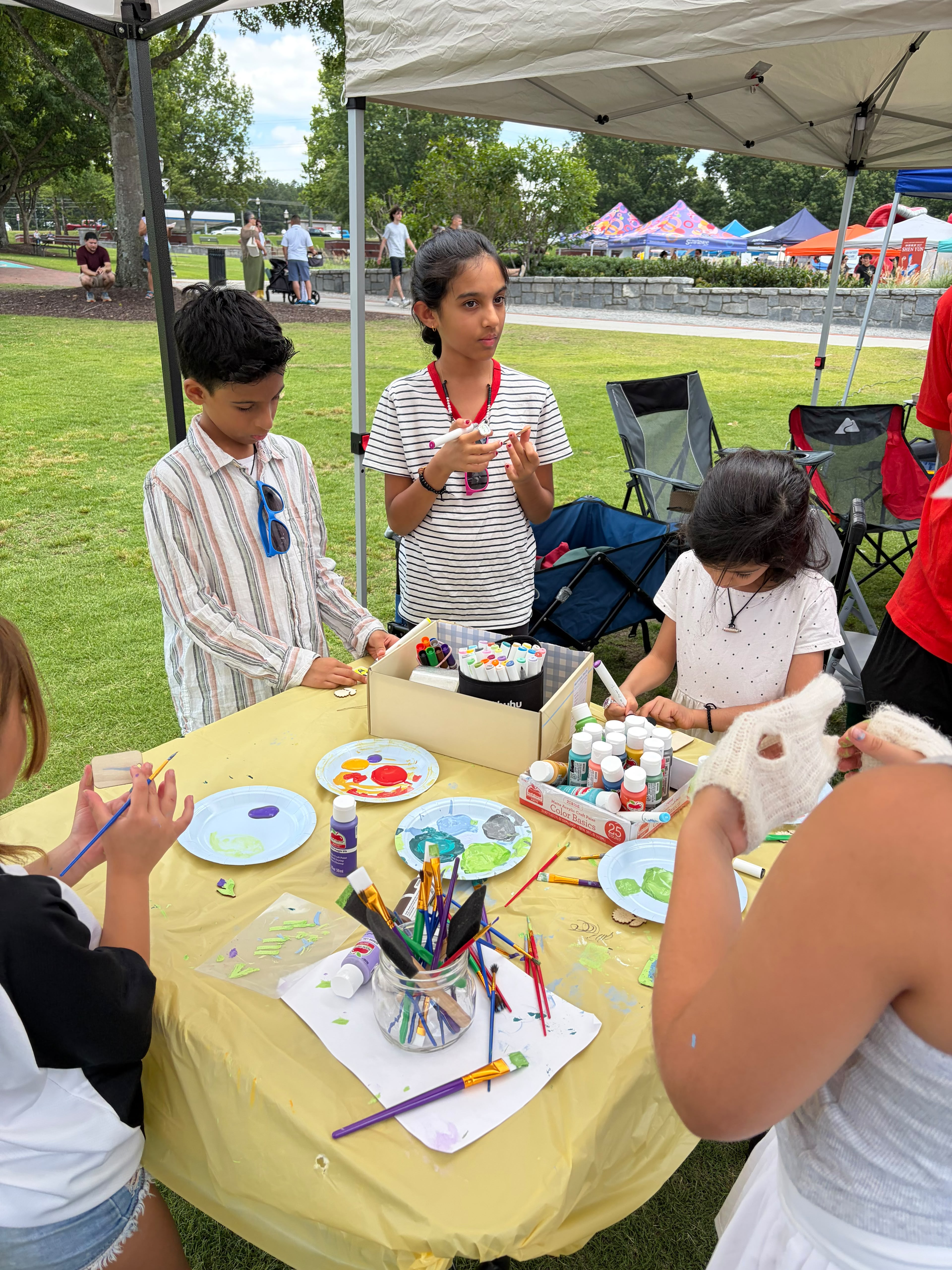 Children painting crafts at a Finance For Movement workshop table.